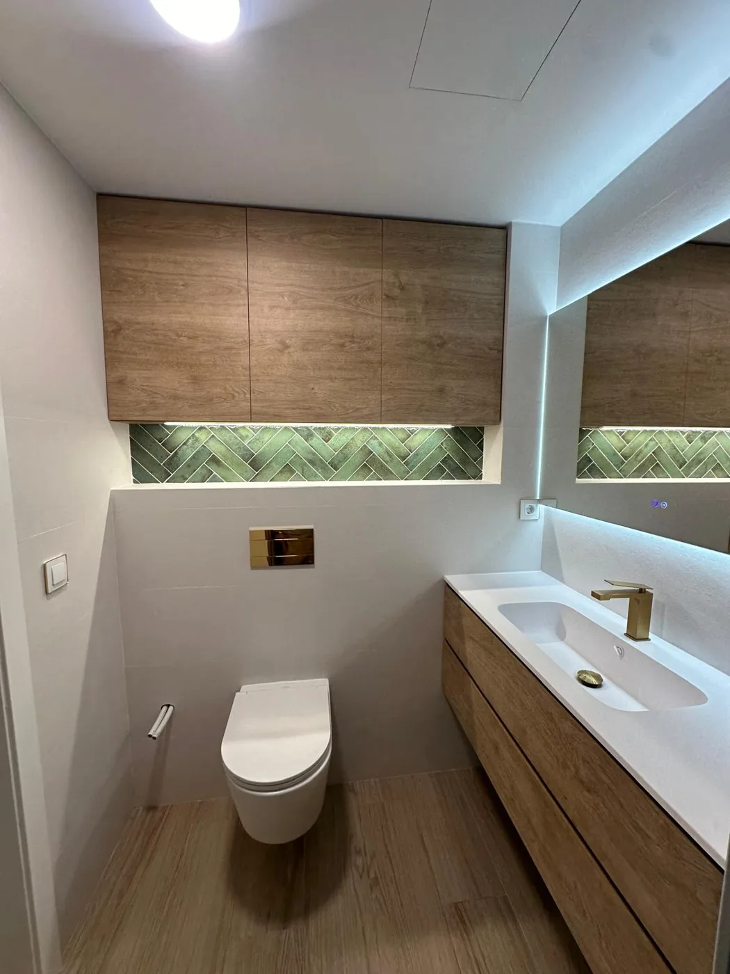 Baño reformado con lavabo de madera y espejo iluminado