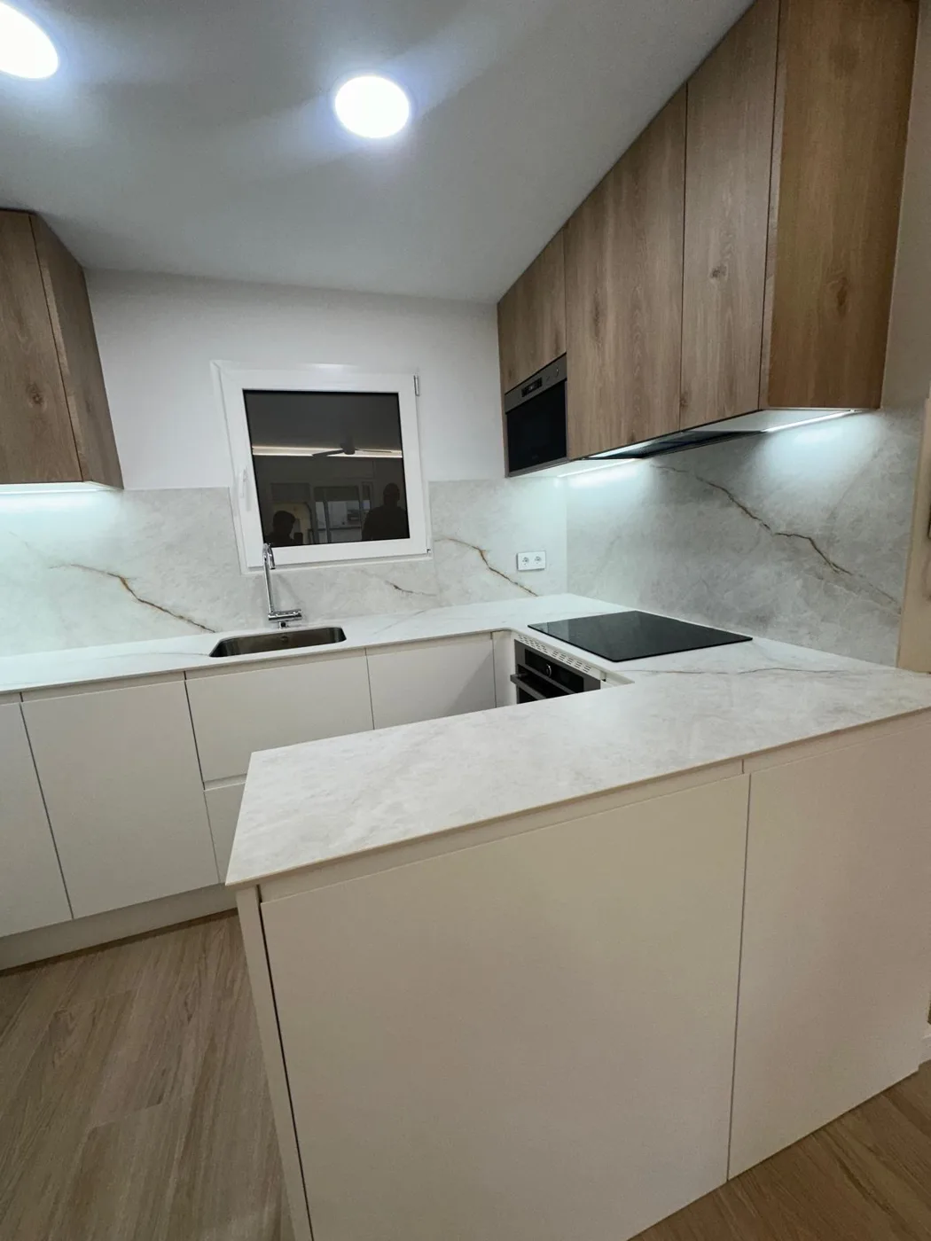 Cocina con barra, muebles blancos y armarios de madera