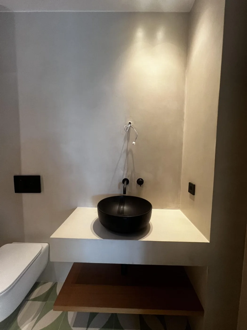 Baño con paredes de acabado continuo y lavabo negro