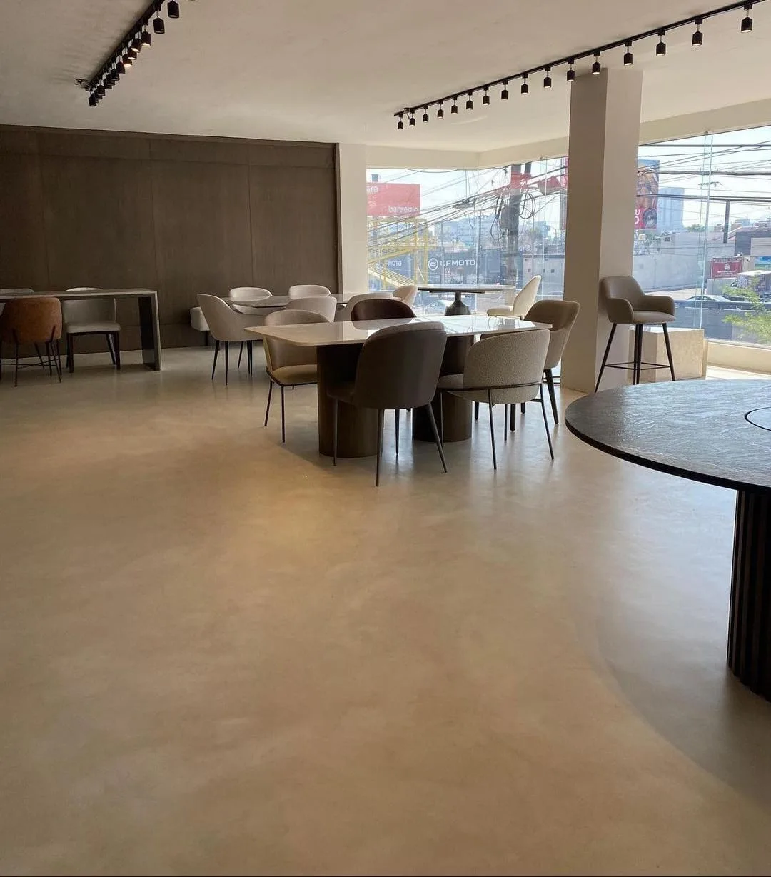 Pavimento continuo de microcemento en un interior con mesas y sillas